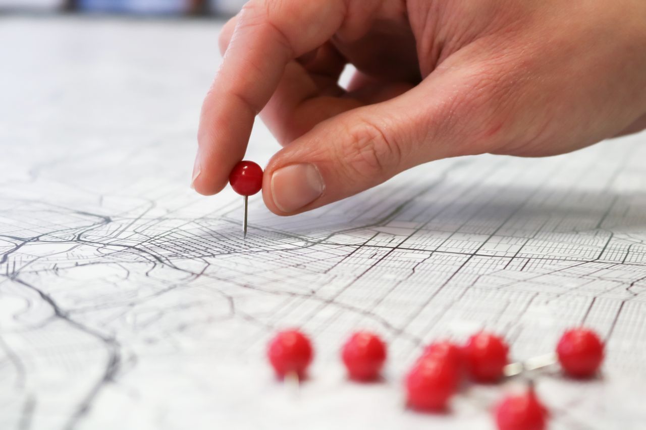 Hand placing a pin on a map — plotting the A/B testing roadmap